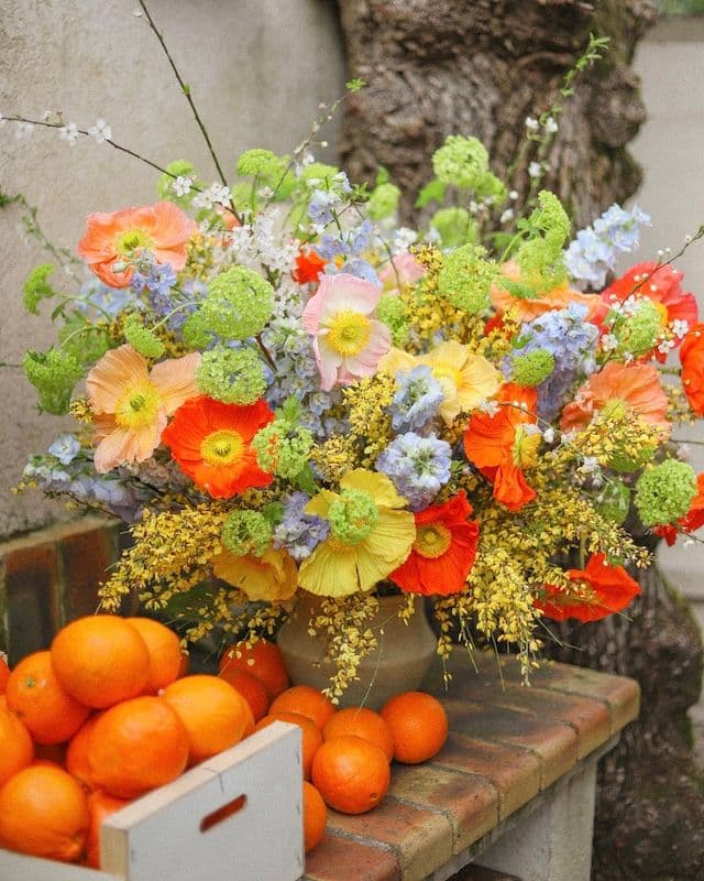 Composition florale avec coquelicots multicolores, genêt jaune et delphinium bleu