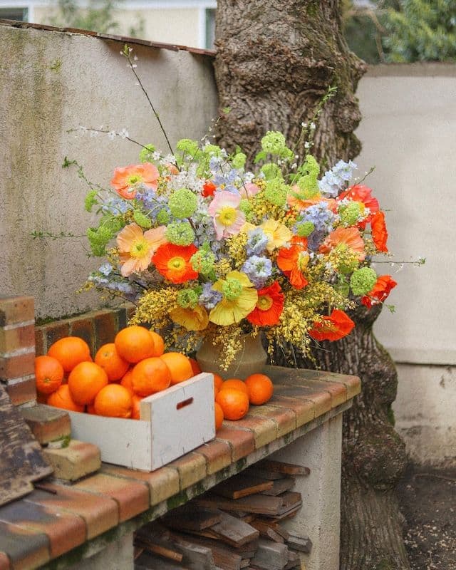 Composition florale avec coquelicots multicolores, genêt jaune et delphinium bleu